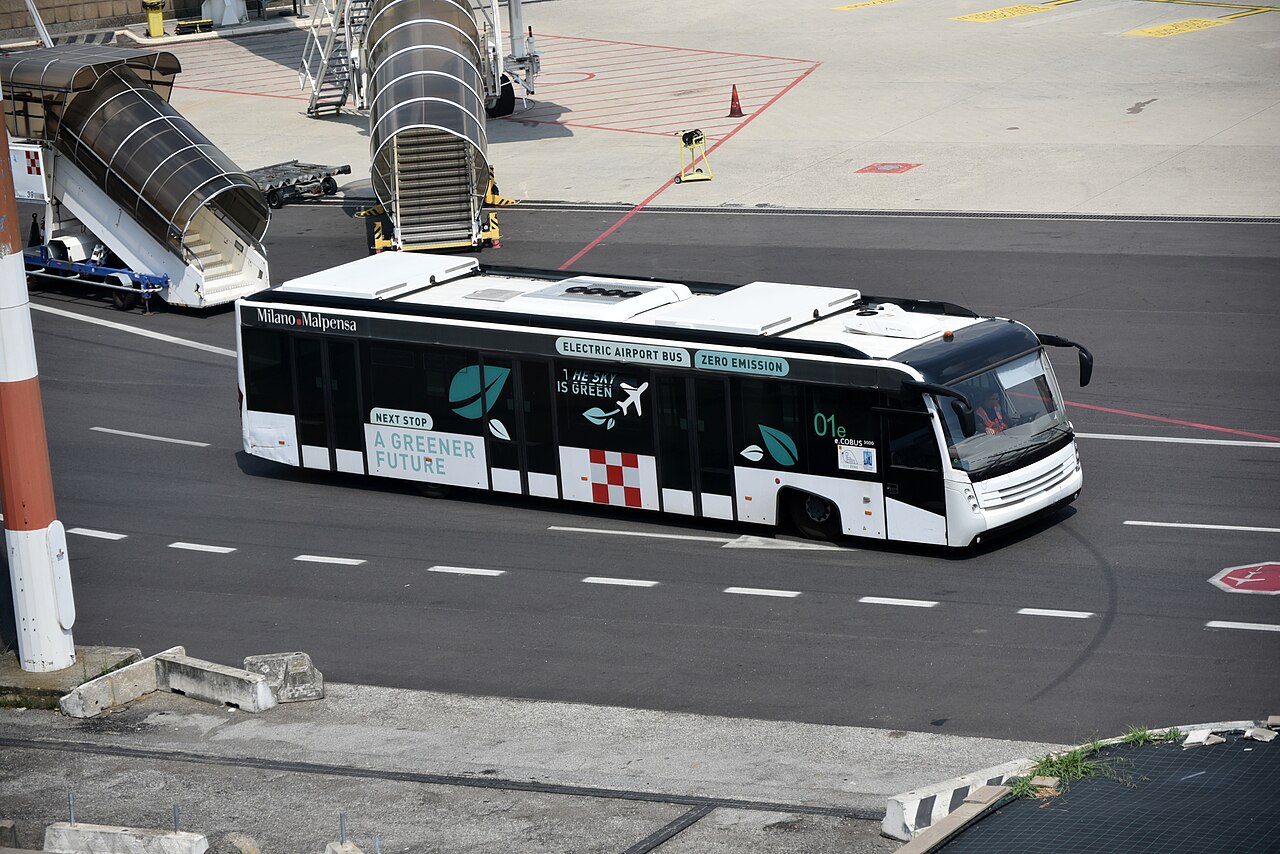 A white electric e.Cobus 3000 airport apron bus at Milan Malpensa Airport