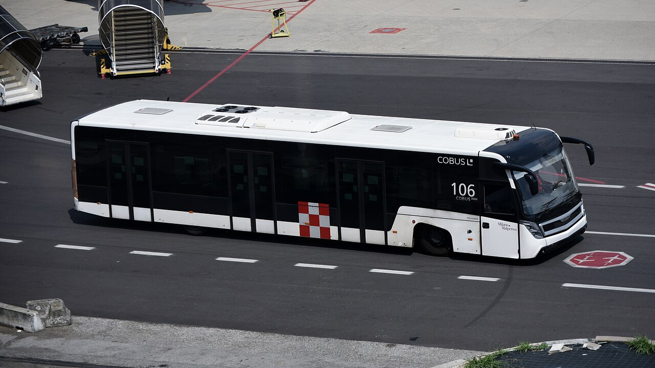 A white Cobus 3000 airport apron bus at Milan Malpensa Airport, used to transfer passengers to aircraft.