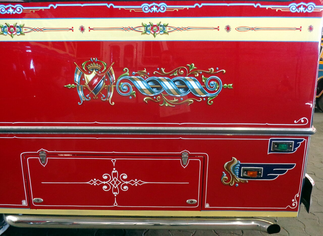 A close-up of fileteado painting on the side panel of a Buenos Aires colectivo, with colorful scrolls and shaded lines.