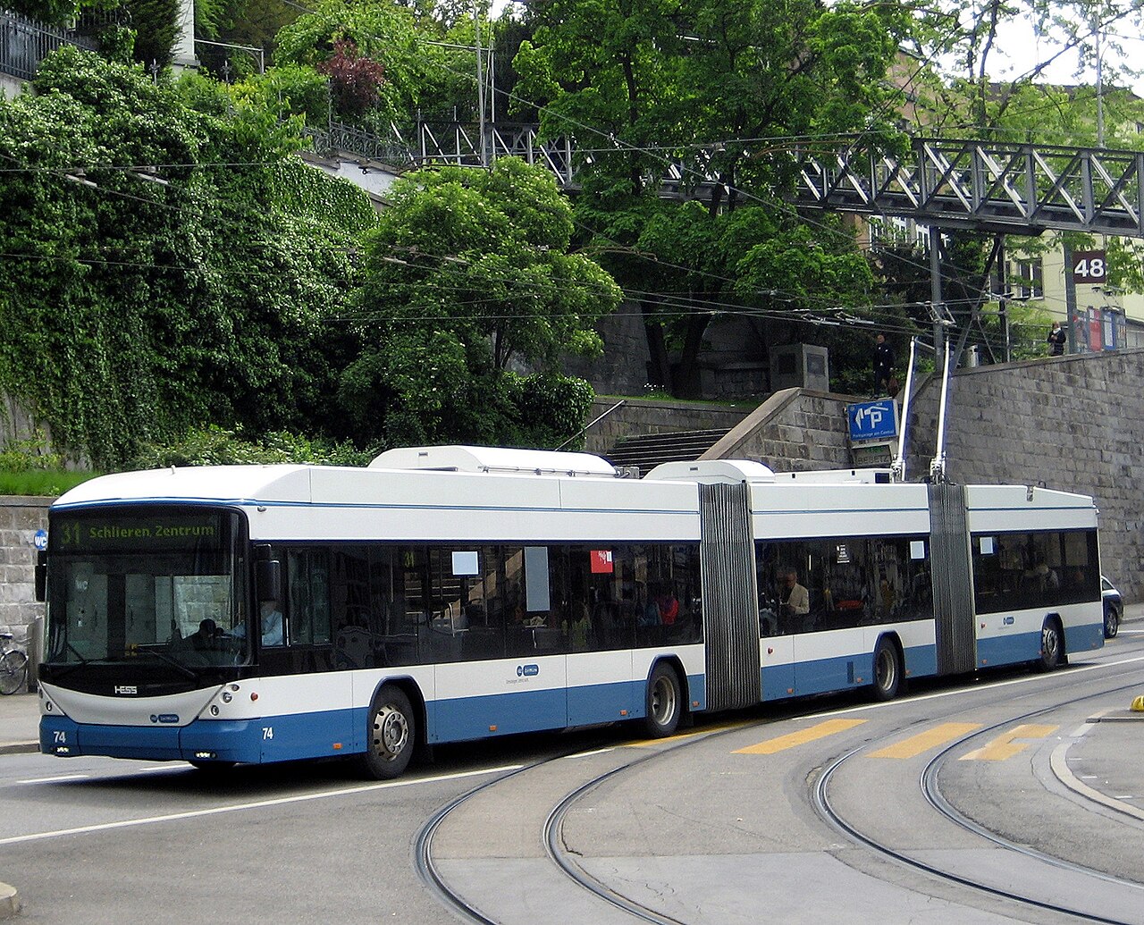 A modern double-articulated Hess trolleybus in Zurich drawing power from overhead wires on a city street.