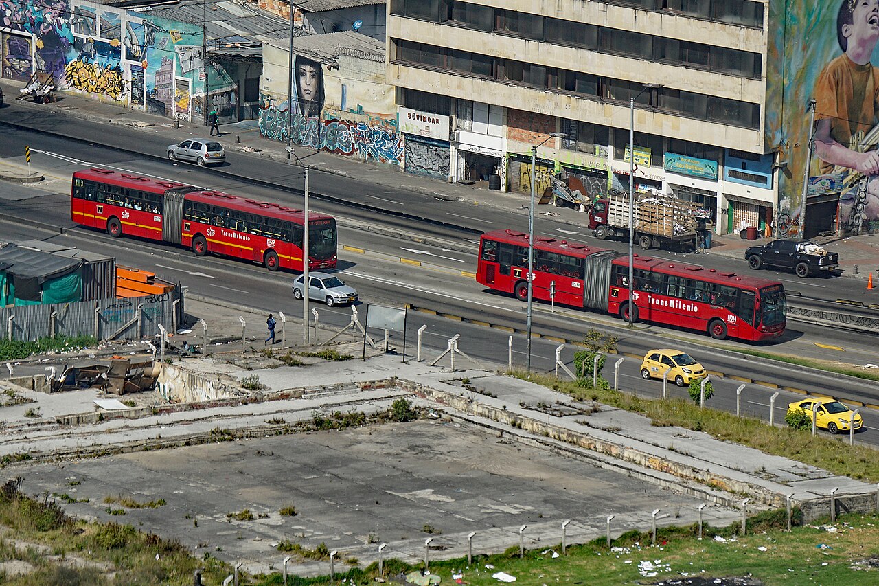 Red articulated TransMilenio buses on a dedicated busway in Bogotá, Colombia