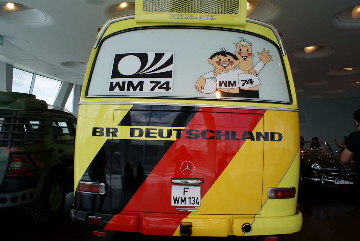 Rear of the West Germany O302 showing the WM 74 World Cup logo, the Tip and Tap mascots, the German tricolour and a roof-mounted Thermo King air-conditioning unit.