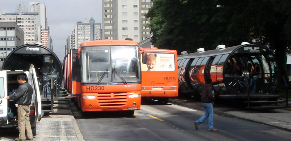 Two bi-articulated buses loading passengers at a tube station on a Curitiba BRT corridor