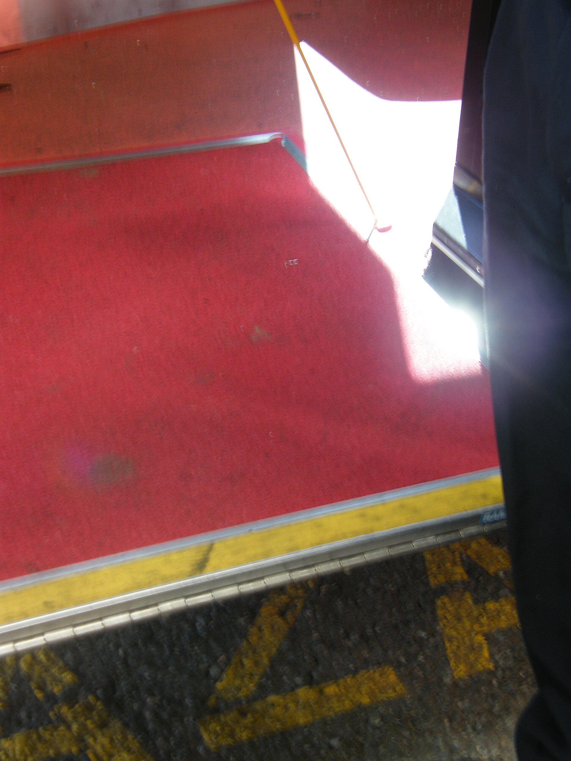 Close-up of a deployed 890-millimetre bus boarding ramp bridging the gap between the kerb and the low floor of the bus.
