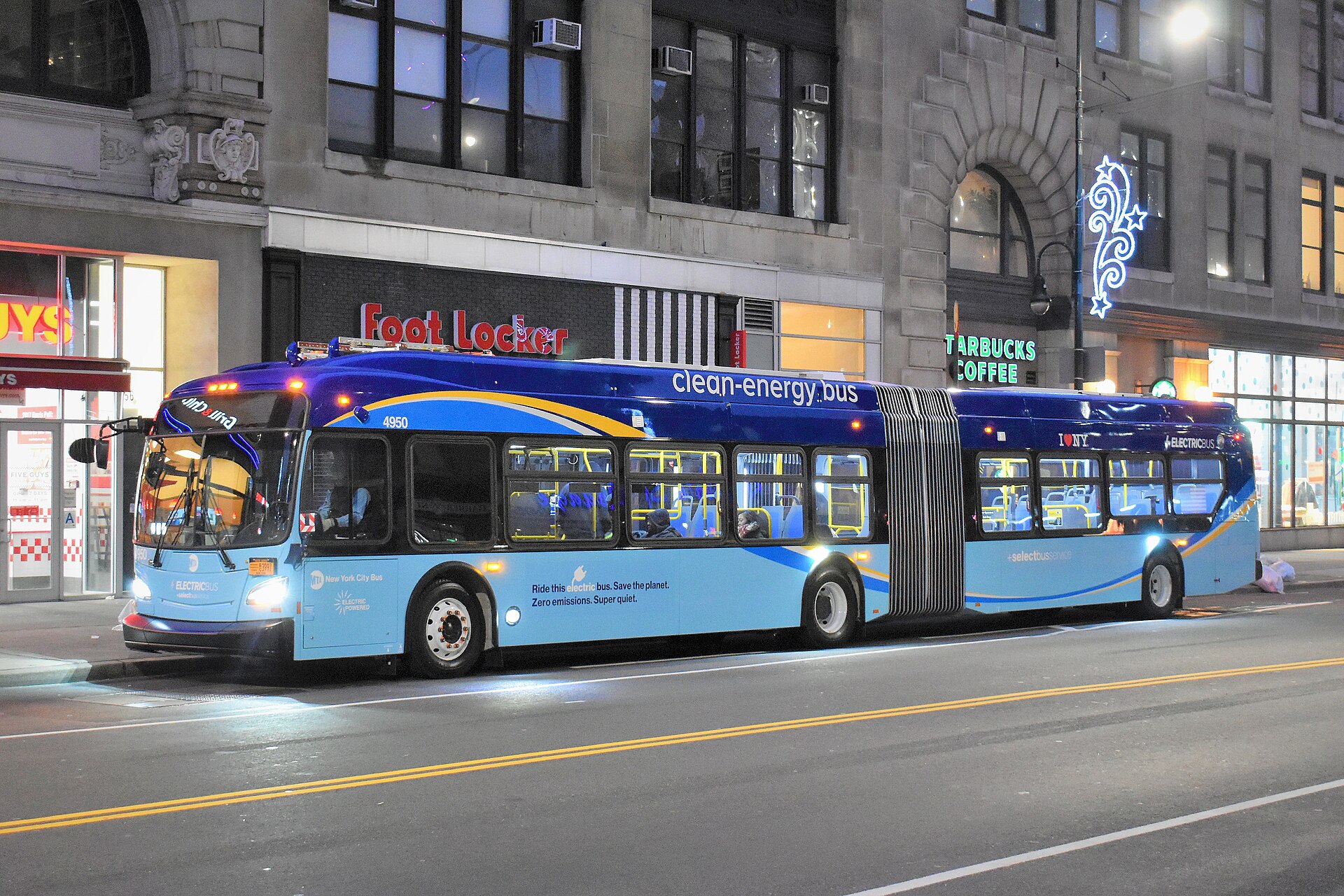 An all-electric New Flyer Xcelsior XE60 articulated bus on the M14 Select Bus Service in Manhattan, New York, before dawn.