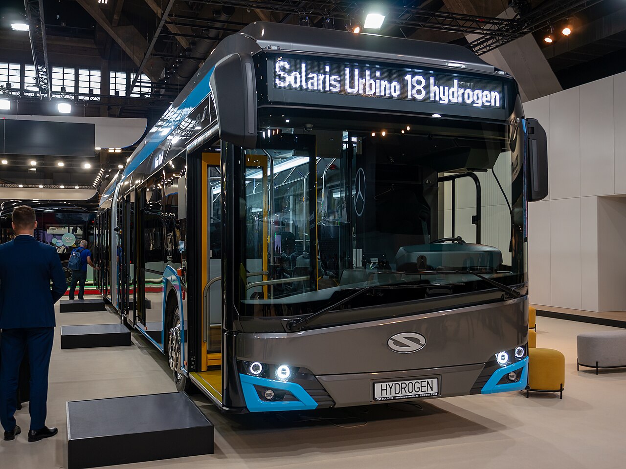 A long articulated Solaris Urbino 18 city bus with a concertina joint in the middle, on display at Busworld Europe 2023.