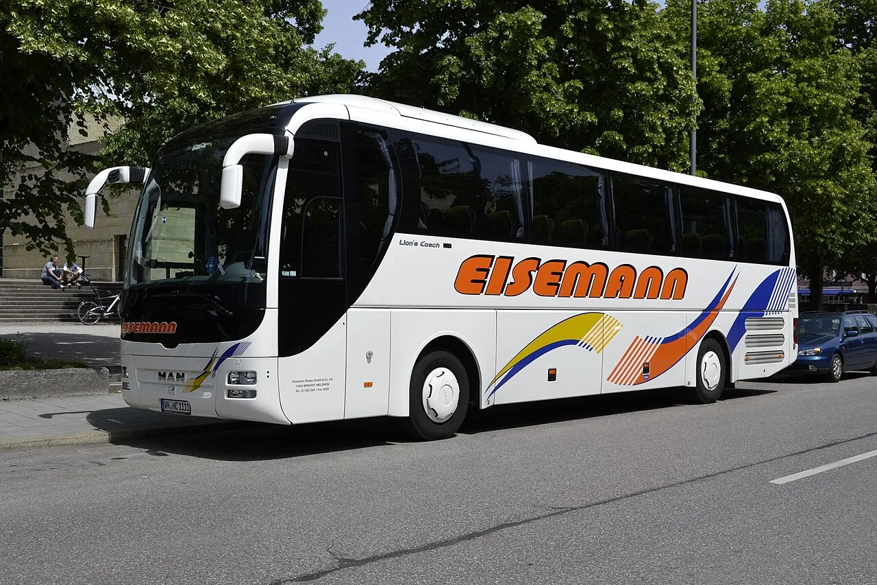 A white MAN Lion's Coach high-deck touring coach parked in Munich, Germany.