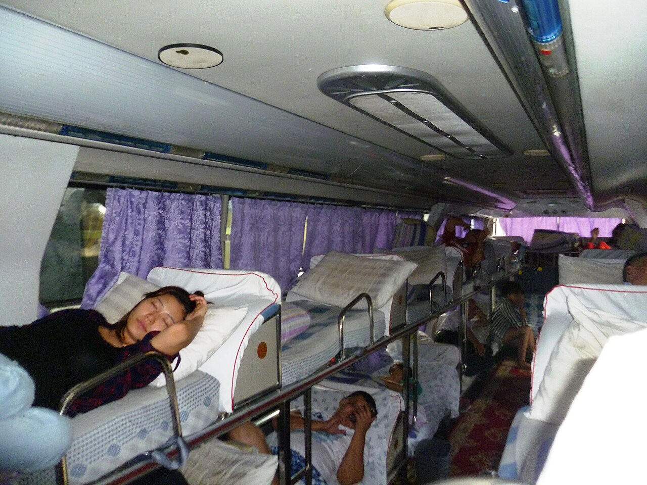 The bunk-lined interior of a Chinese sleeper bus, with stacked berths in a 2+1 layout
