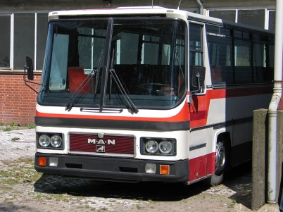 MAN UEL classic urban bus in red and white livery parked outdoors, front view showing rectangular headlights and large windshield design.
